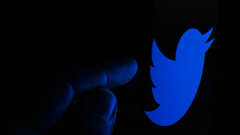 hand touching twitter logo shadow finger