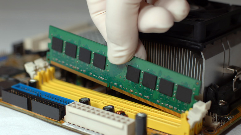 Person installing a RAM module into a PC motherboard