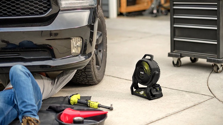 Person using Limited Edition Ryobi fan while working under a vehicle