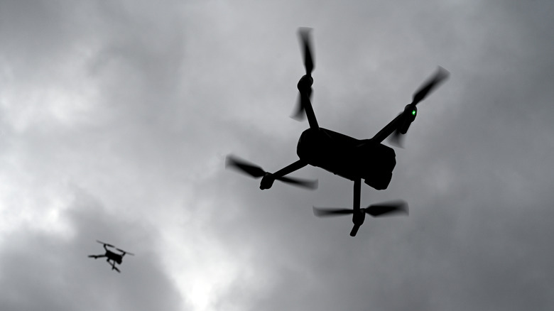 Flying drones silhouetted against the sky.