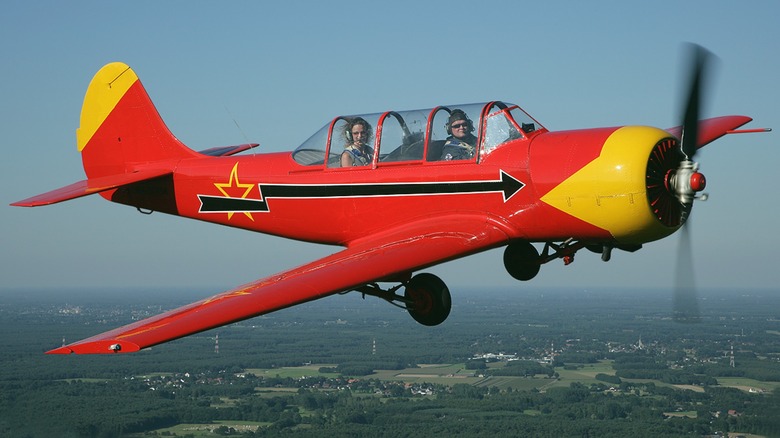 Man and woman in red and yellow Yak-52 prop plane