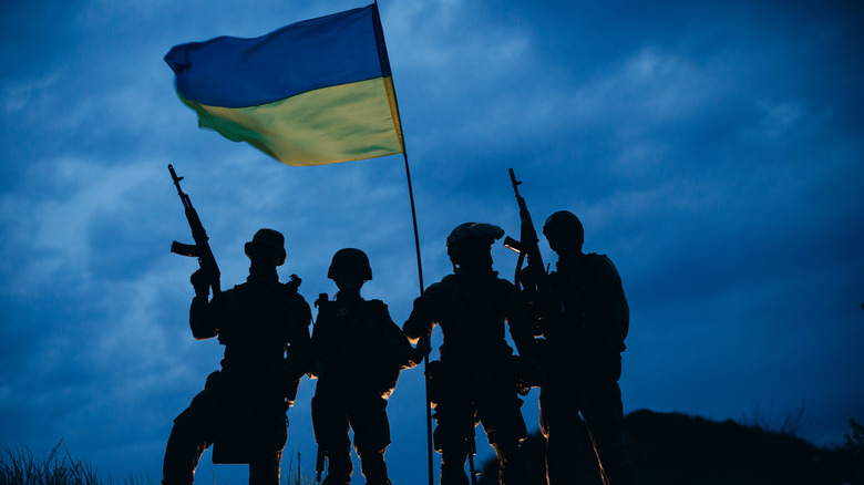 A group of armed Ukrainian warriors with a national flag in the evening