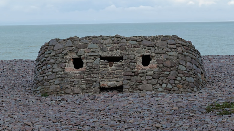 A dilapidated military pillbox shelter on a beach.