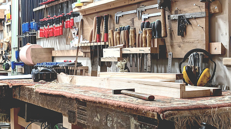 A heavily-used wood workbench surrounded by tools