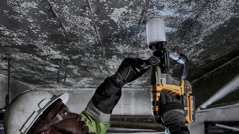 Man using DeWalt Hammer Drill on concrete on ceiling