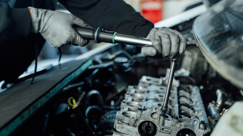 Mechanic using torque wrench on cylinder head bolt