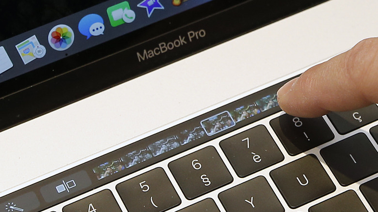 Person interacting with MacBook Pro Touch Bar.