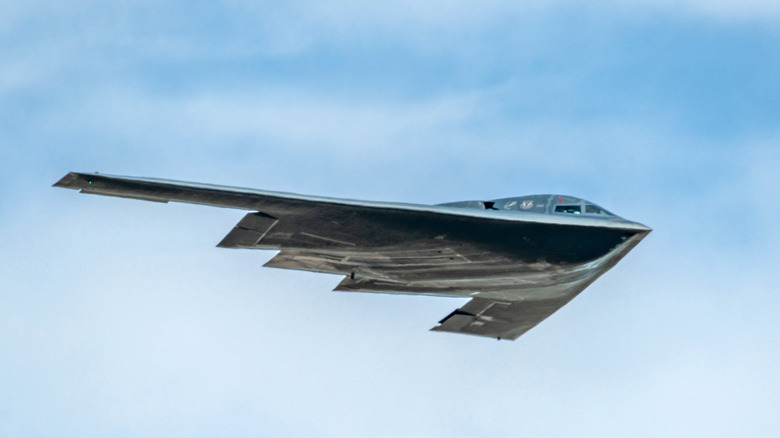 A B-2 bomer in flight against a blue sky