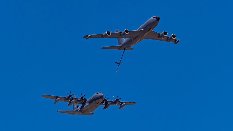 Ground view of KC-135R tanker performing simulated refueling on C-130 transport.