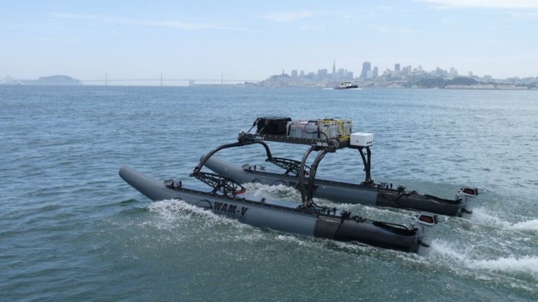 A WAM-V 8 USV on the water with a city skyline in the background