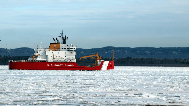 A red United States Coast Guard ship on an icy waterway