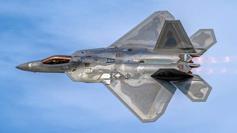 Lockheed F-22 Raptor in banking left turn with afterburner