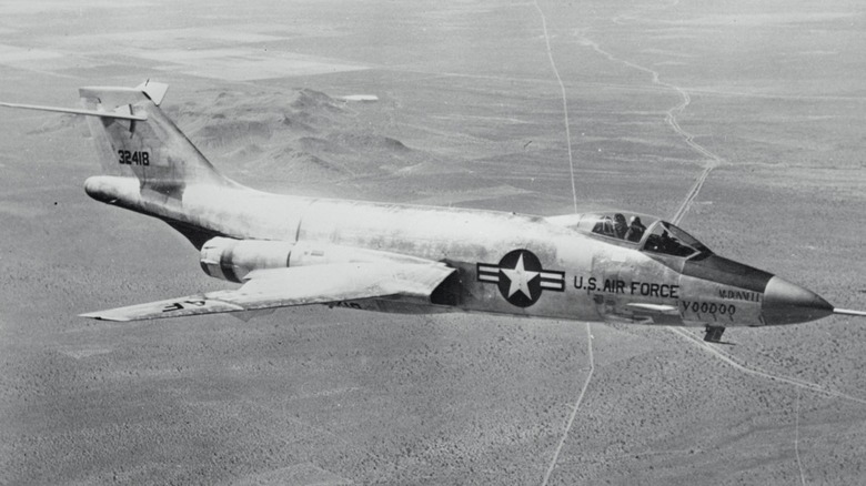 McDonnell F-101 Voodoo flying over wooded terrain