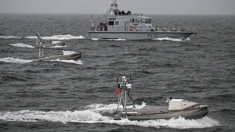 Side view of U.S. Navy drone vessels undergoing training mission with support ship.