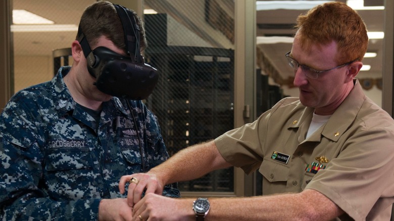 A Lt. Cmdr. works with a sailor using an HTC Vive VR headset