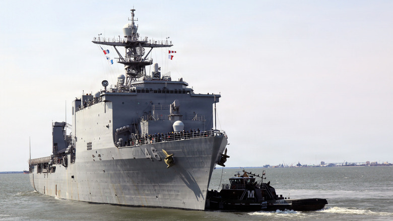 The USS Tortuga heading out to sea after a refit, with the help of a tug boat.