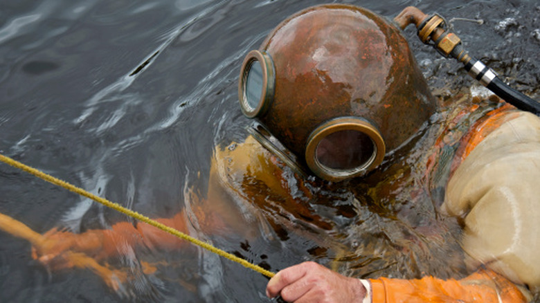 A diver wearing an old-fashioned brass diver's helmet