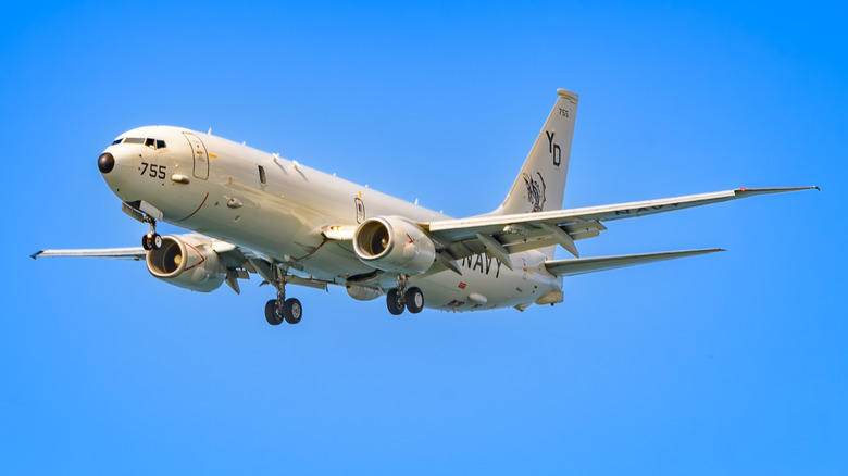 The Boeing P-8A Poseidon with landing gears down with a blue sky in the background.
