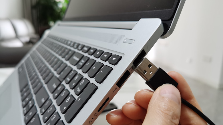 Person plugging USB cable into a laptop