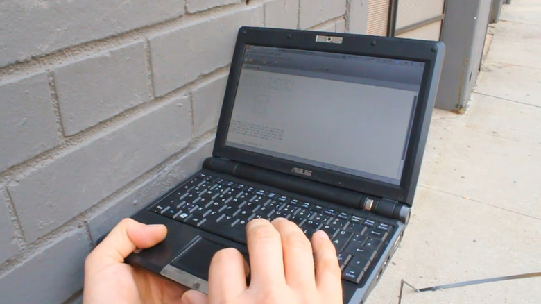 A mini ASUS laptop plugged into a USB drive in a wall.
