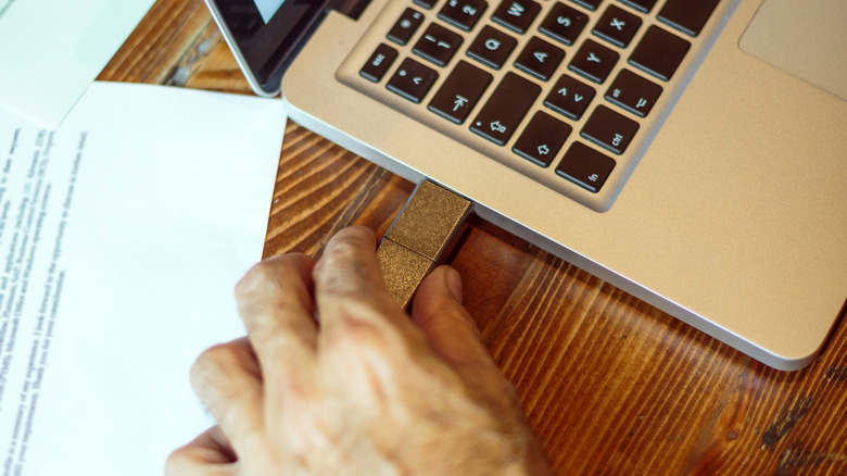A person plugging a USB device into a laptop