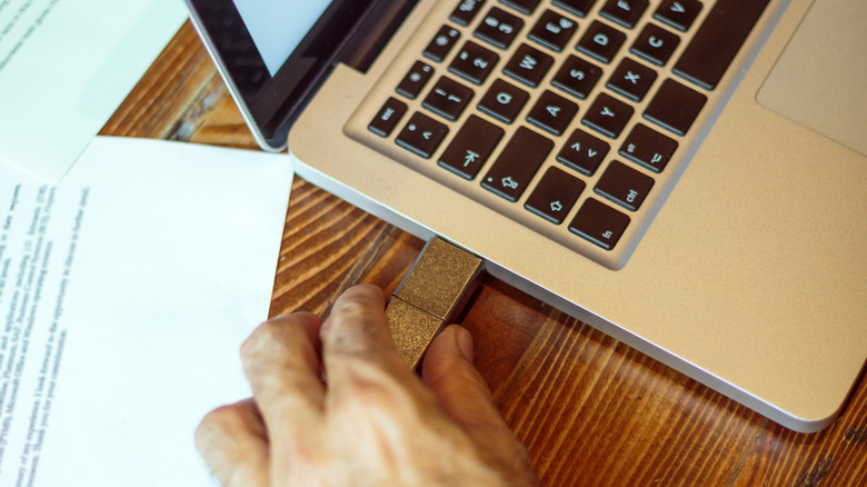 Person plugging in USB device to laptop