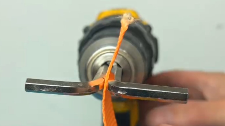 Drill holding a ratchet strap between two hex keys