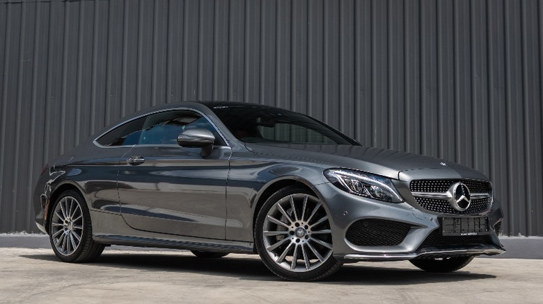 a grey Mercedes-Benz coupe in front of a grey wall