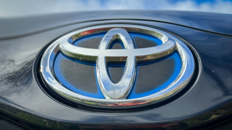 A close-up of a Toyota badge on front of a dark-colored vehicle.