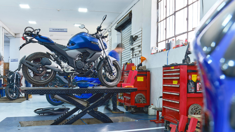 blue Yamaha motorcycle on a lift in a repair shop
