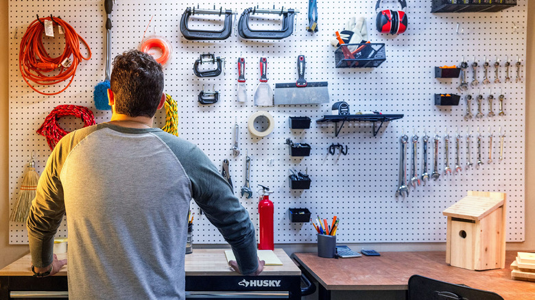 A man looking at a wall full of tools