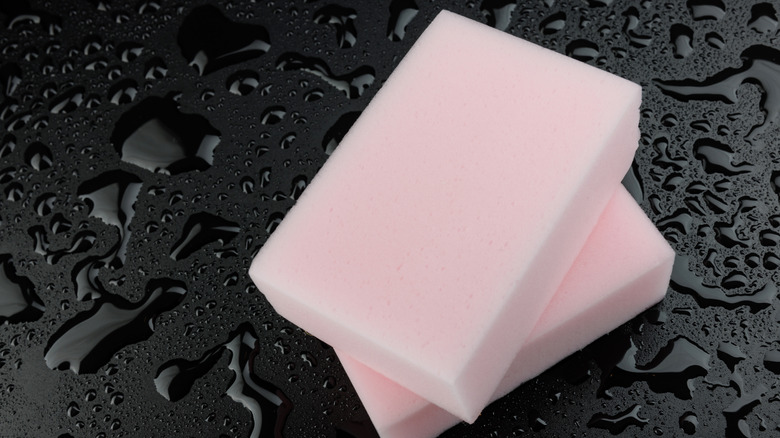 Two melamine sponges on wet black background