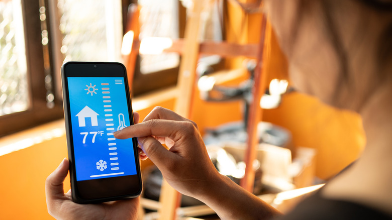 A person adjusting their thermostat using a smartphone