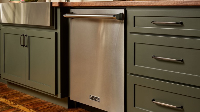 A Viking dishwasher installed next to green kitchen cabinets.