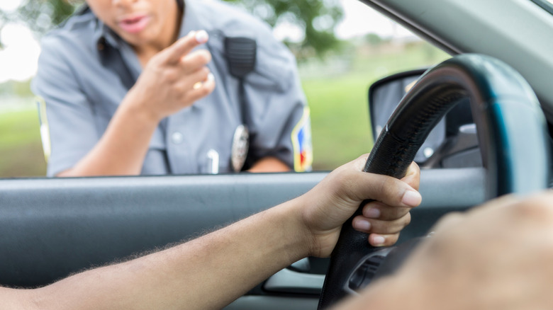 A person being pulled over for speeding with their hands on the wheel