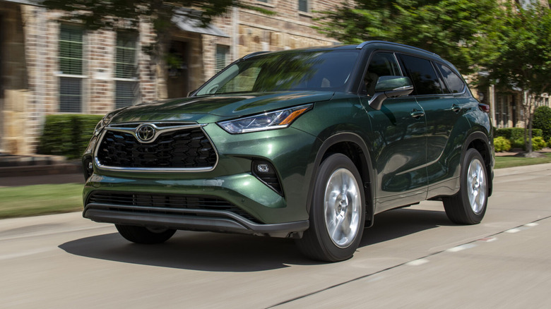A green 2025 Toyota Highlander on front of a building.