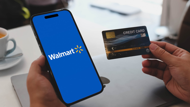 A person holding a phone and a credit card.