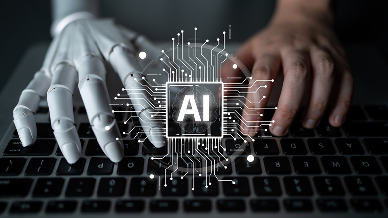 A human and robotic hand typing on a keyboard, with an illustration of an AI chip overlaid