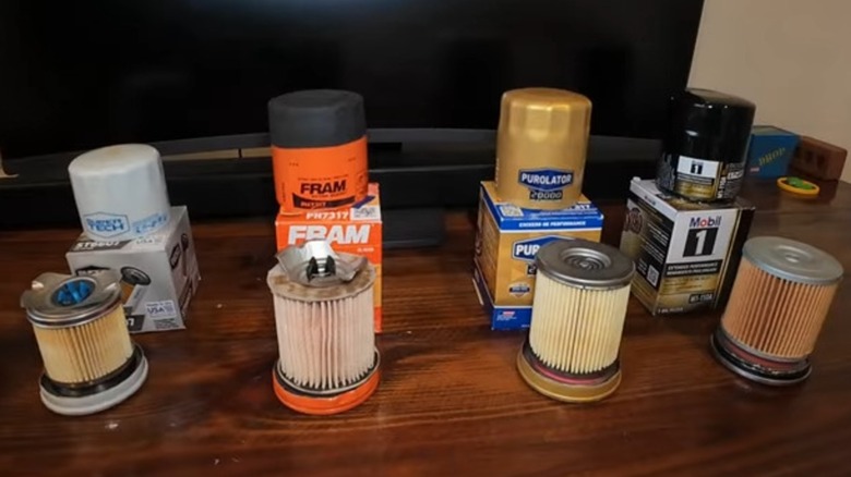 Four brands of oil filters cut open and displayed showing internal structure.