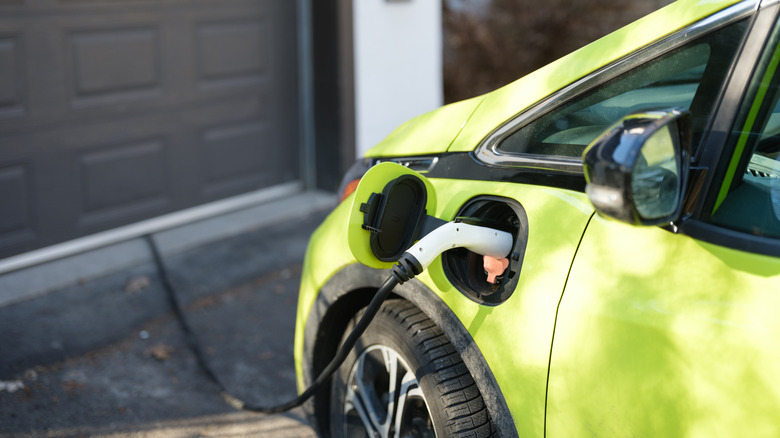 A bright green electric vehicle charging on a driveway
