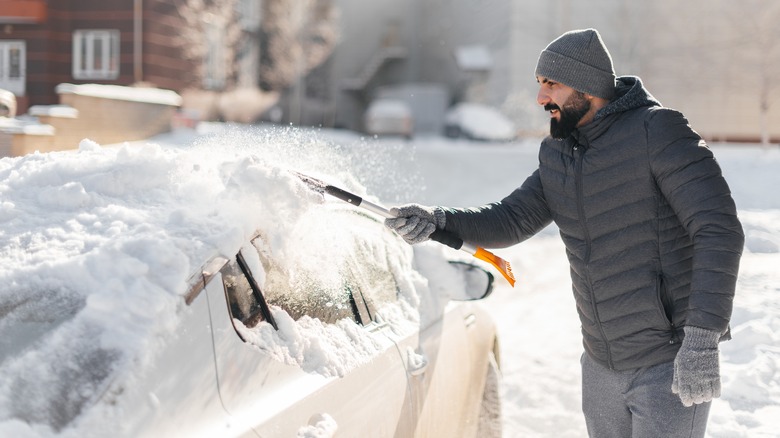 man scraping off snow from car