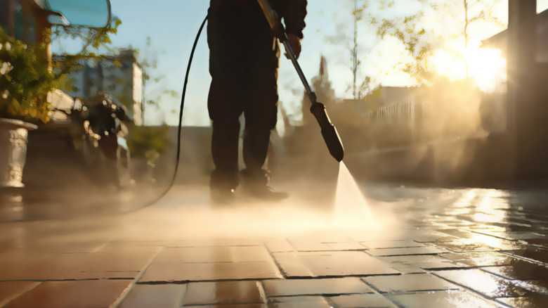 Person cleaning driveway with pressure washer