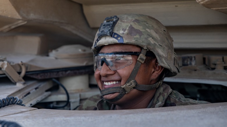 A U.S. Army Soldier smiling while sitting in the driver seat of a M1A2 SEP V3 Abrams Main Battle Tank