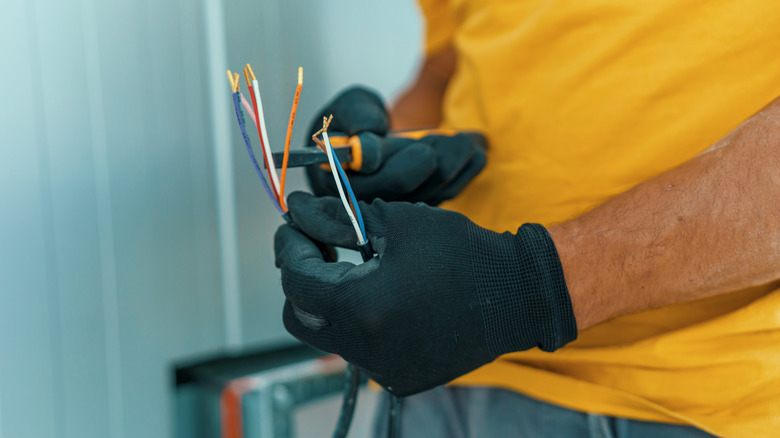 A person holding exposed wires and pliers.