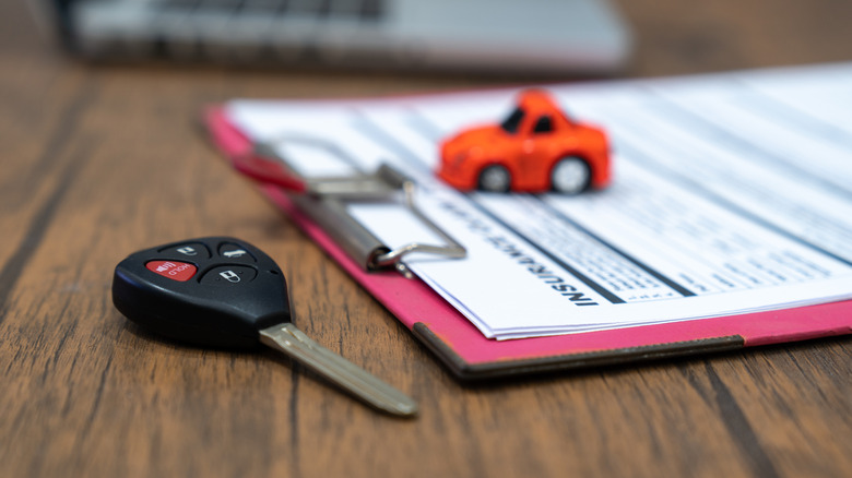 A car key beside insurance documents.