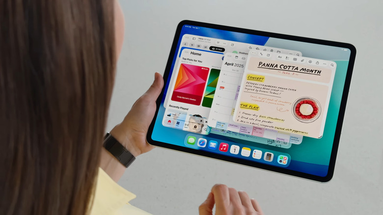 Woman holding iPad with iPadOS 26 showing multiple open windows