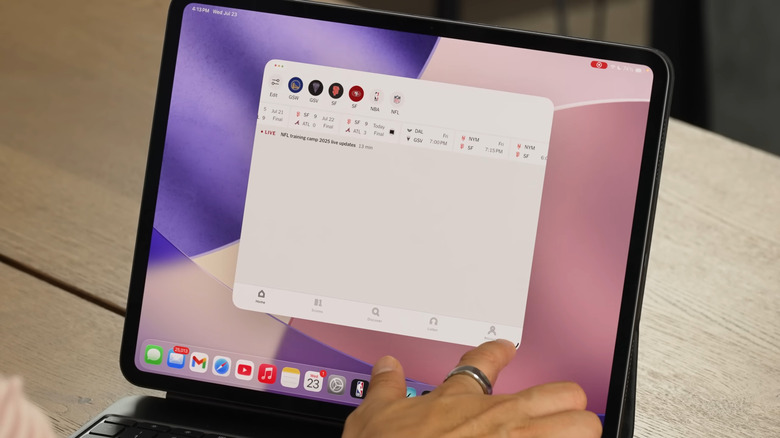 Hand touching grab handle for a window in iPadOS 26