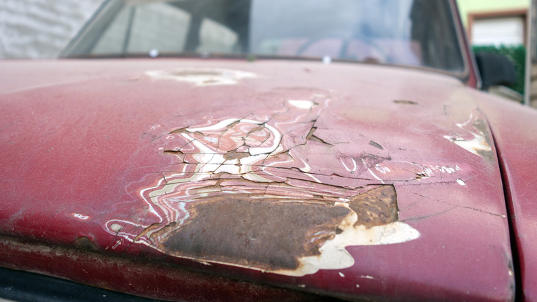 Rust formation on classic car showing layers of red paint eaten away by corrosion