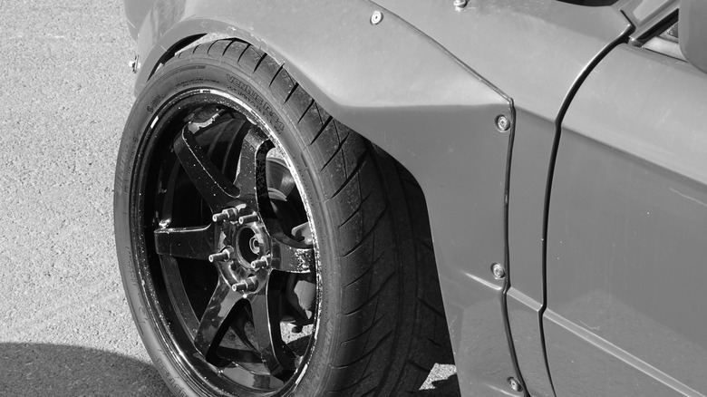 A wide tire and six-spoke wheel under a bolted-on fender flare