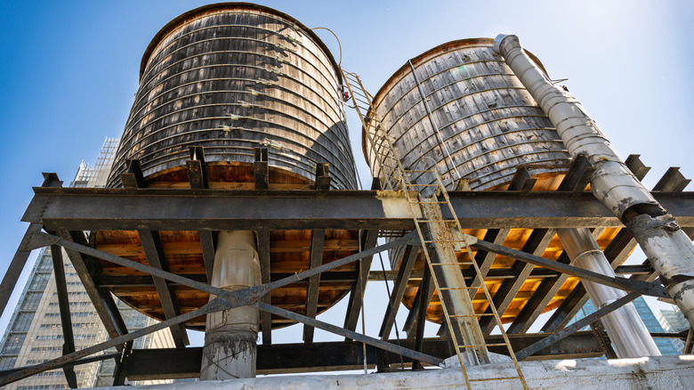 Rooftop view of two wooden water tanks with metal supports and ladders